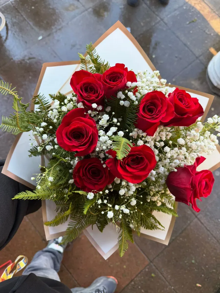 Ramo de ocho rosas rojas con gypsophila y follaje verde